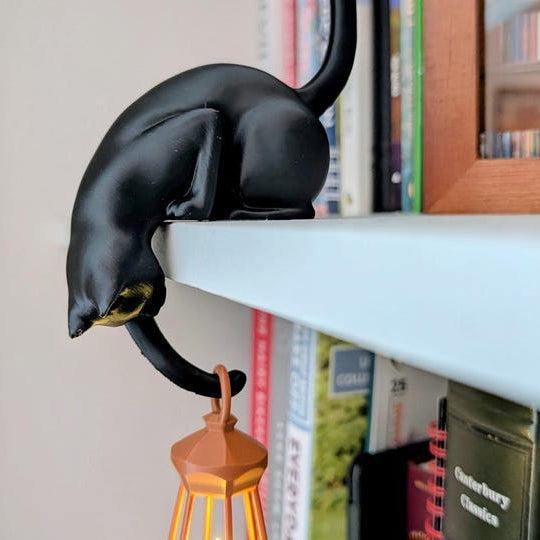 Black Nookglow cat shelf lantern glowing on a bookshelf